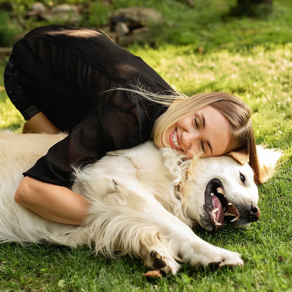 woman hugging dog in grass